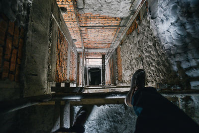 Low section of man standing next to a lift shaft in a building under construction