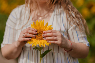 Midsection of woman holding yellow flower