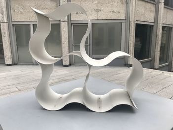 Close-up of white sculpture on table against window of building