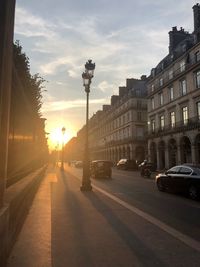 Cars on street in city against sky during sunset