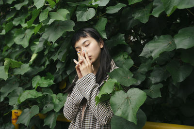 Beautiful young woman standing against plants