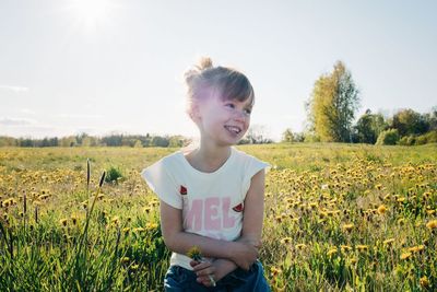 Portrait of a young girl sat in a field of flowers smiling