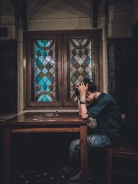 Side view of woman sitting on window