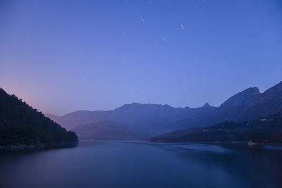 Scenic view of lake against clear blue sky at dusk