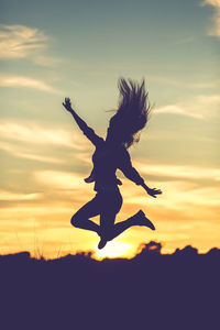 Silhouette woman jumping at sky during sunset