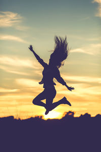 Silhouette of person jumping at sunset