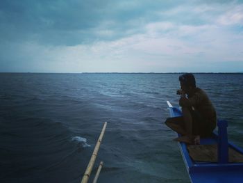 Rear view of a man overlooking calm sea