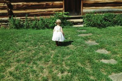 Rear view of girl walking on field towards house