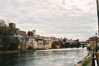 Houses by river in town against sky