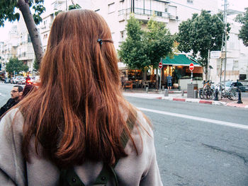 Rear view of woman with umbrella walking on road in city