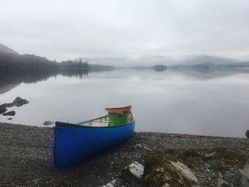 Boat moored on lake against sky