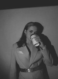 Portrait of young woman standing against wall at home
