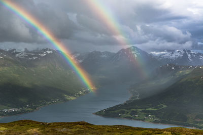 Scenic view of rainbows over lake and mountains