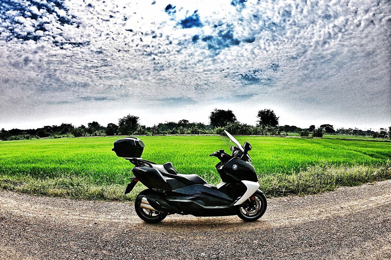 plant, sky, transportation, mode of transportation, tree, land vehicle, cloud - sky, nature, grass, day, motorcycle, land, field, real people, road, outdoors, sunlight, landscape, beauty in nature, environment, riding