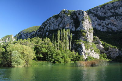 Scenic view of river by mountains against clear sky