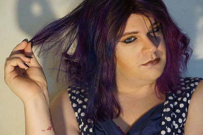 Close-up portrait of transgender male against wall