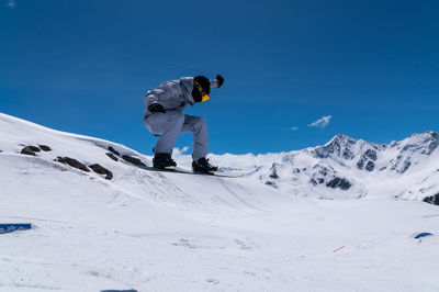 Portrait of a young man snowboarder jumping on a snowboard in sportswear, against the backdrop of