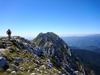 Rear view of man walking on mountain against clear blue sky