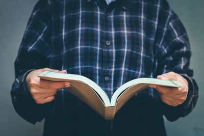 Midsection of man reading book