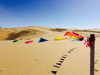 Multi colored flags in desert against clear sky