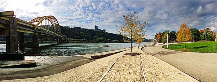 Footpath by bridge against sky