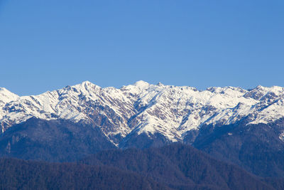 Scenic view of snowcapped mountains against clear blue sky