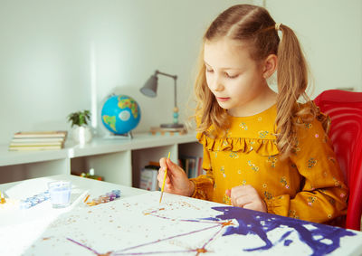 Cute girl painting while sitting at home