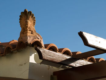 Low angle view of sculptures on building against clear blue sky