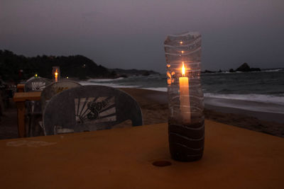 Illuminated lighting equipment on beach against sky at night