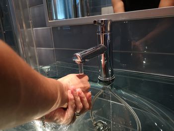 Cropped image of person washing hands under faucet