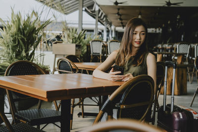 Young woman sitting on chair at outdoor cafe