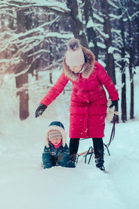 Mother and daughter wearing warm clothing playing in snow during winter