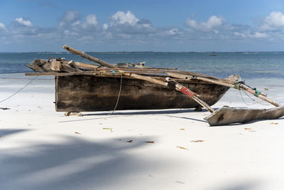 Fishing boat on beach against sky