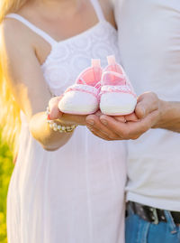 Midsection of couple holding baby shoes