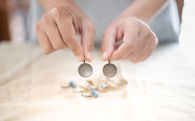 The female hands holding and choosing the wood plate frame earring for embroidery thread.