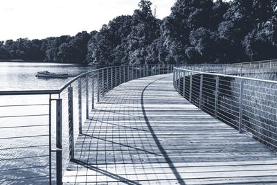 Boardwalk amidst trees against sky