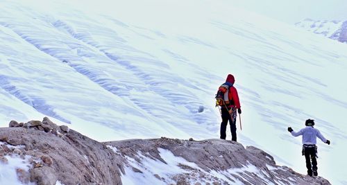 Rear view of people on snowcapped mountain