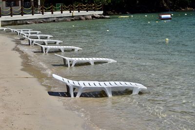 Empty chairs on beach by sea