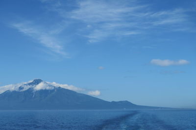 Scenic view of sea and mountains against blue sky