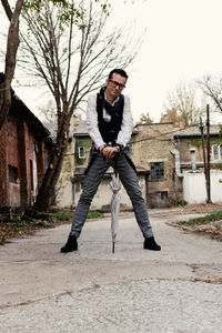 Low angle view of mid adult confident man with umbrella standing on the street.