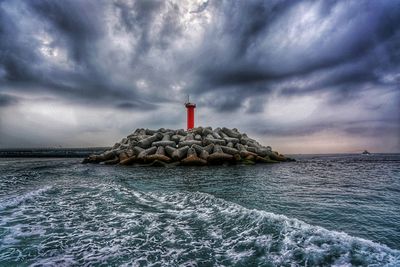 Lighthouse by sea against sky