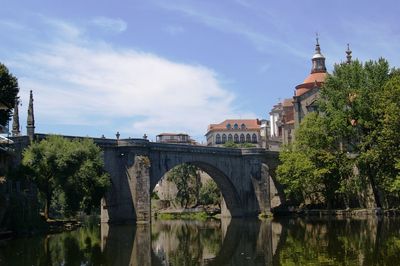 Bridge over river by cathedral against sky