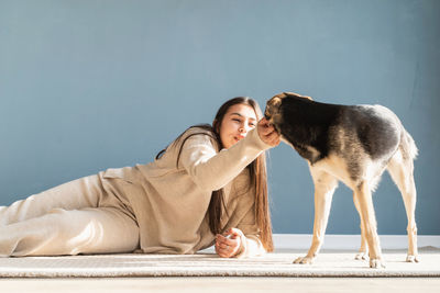 Beautiful brunette woman with playful mixed breed dog, embracing and having fun at home