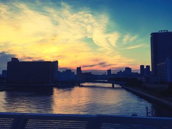 River by city against sky during sunset