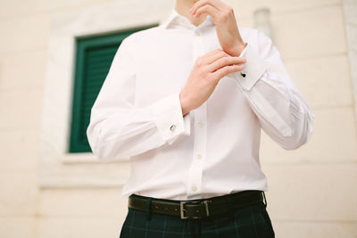 Midsection of man holding white standing against wall