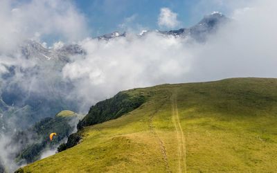 Scenic view of green mountain before clouds and high alps