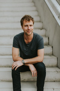 Portrait of young man sitting on staircase