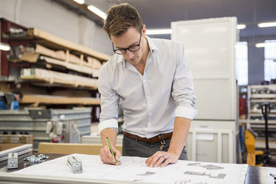 Young businessman in factory working on plan