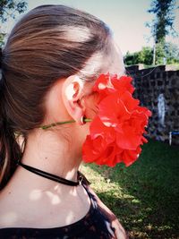 Side view of young woman wearing flowers in ear