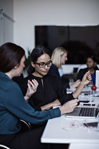 Businesswomen working over laptop at conference table in board room